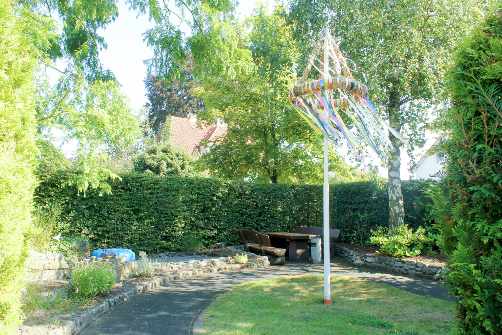 Gartenbereich mit Sitzgruppe und geschmücktem Maibaum