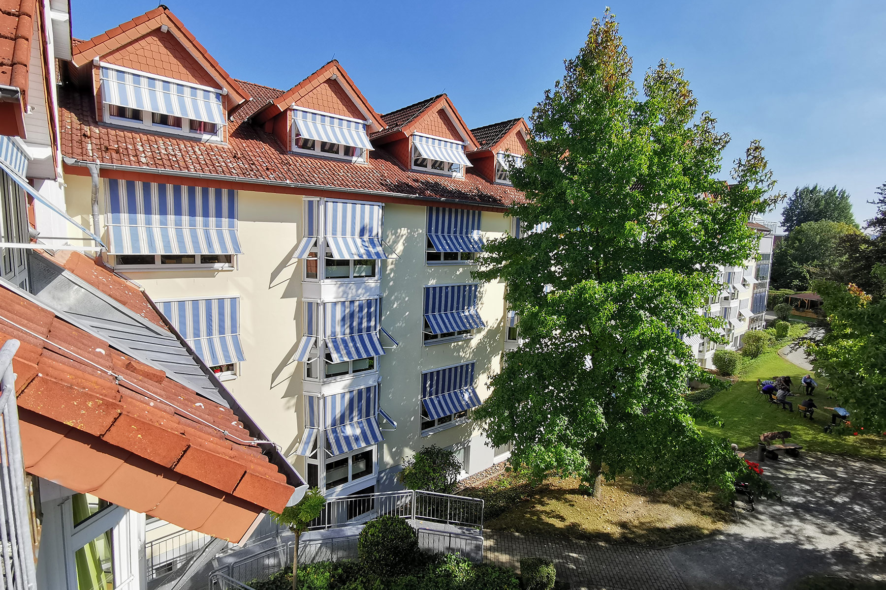 Blick in den Park und auf die Hausfront mit Balkonen und Loggien