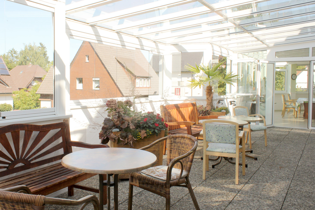 Überdachte Terrasse mit Tischen, Stühlen und Bänken, Blick auf Wohnbebauung