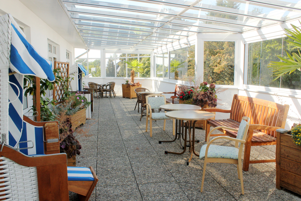 Überdachte Terrasse mit Tischen, Stühlen und Strandkörben